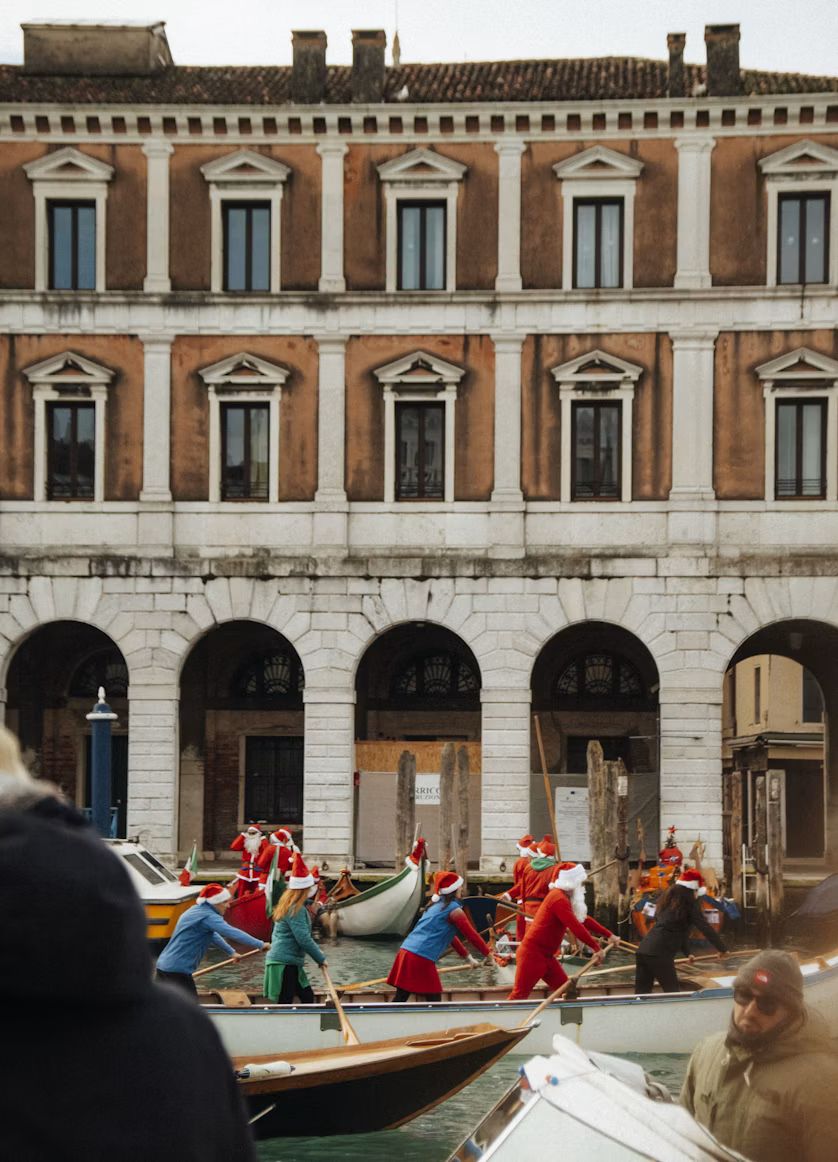Ruderer in Weihnachtsmann-Kostümen vor einem Palazzo am Canal Grande